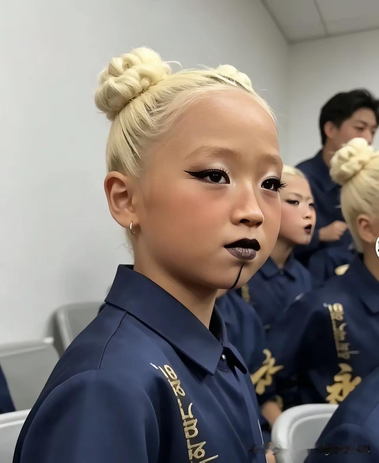 五六岁的小姑娘。
满头白发。
眼线黑乎乎的。
嘴唇也是黑的。
下巴还画一道黑线。