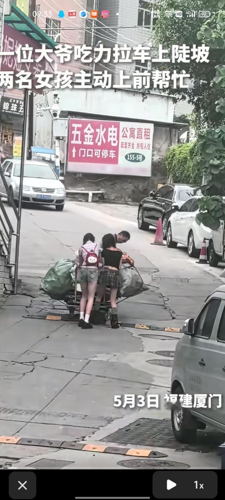 5月3日，福建厦门。大爷吃力的拉着一辆装满货物的平板车上陡坡，两位刚好经过的女生