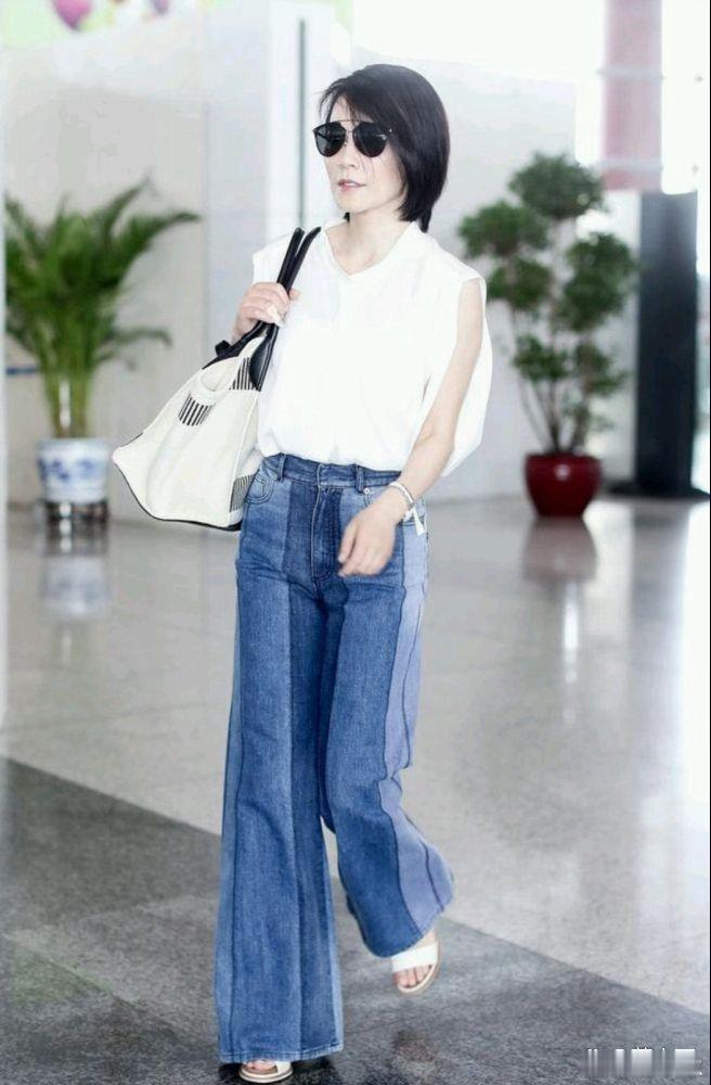 俞飞鸿机场私服审美在线，白无袖上衣搭配喇叭裤，简约搭配洋气又出彩。 