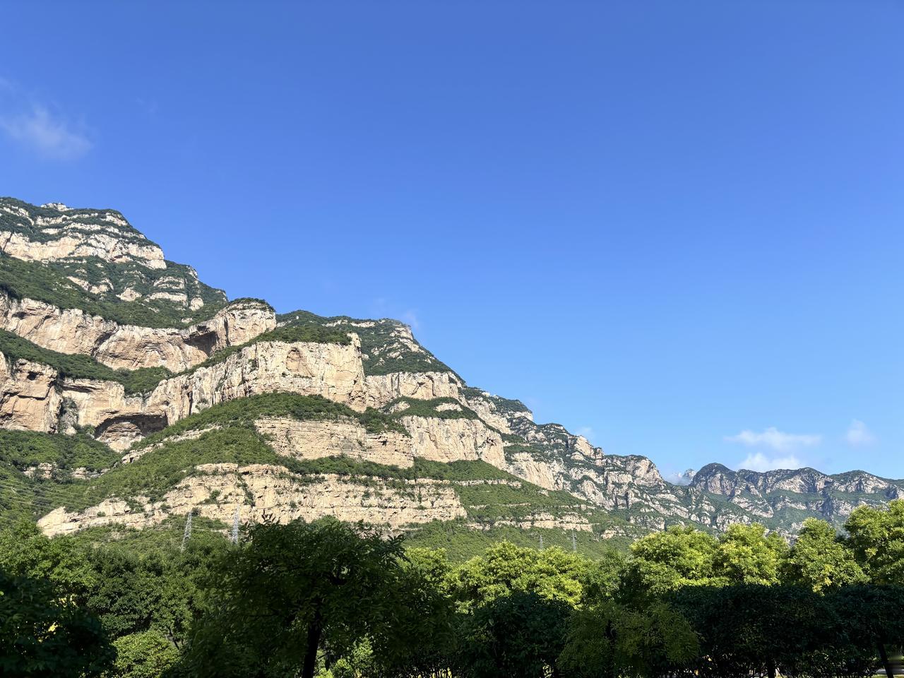 站在高高的山岗上，俯瞰山间万物，山是绿的，水是碧的，天是蓝的，风是柔的，大地是辽