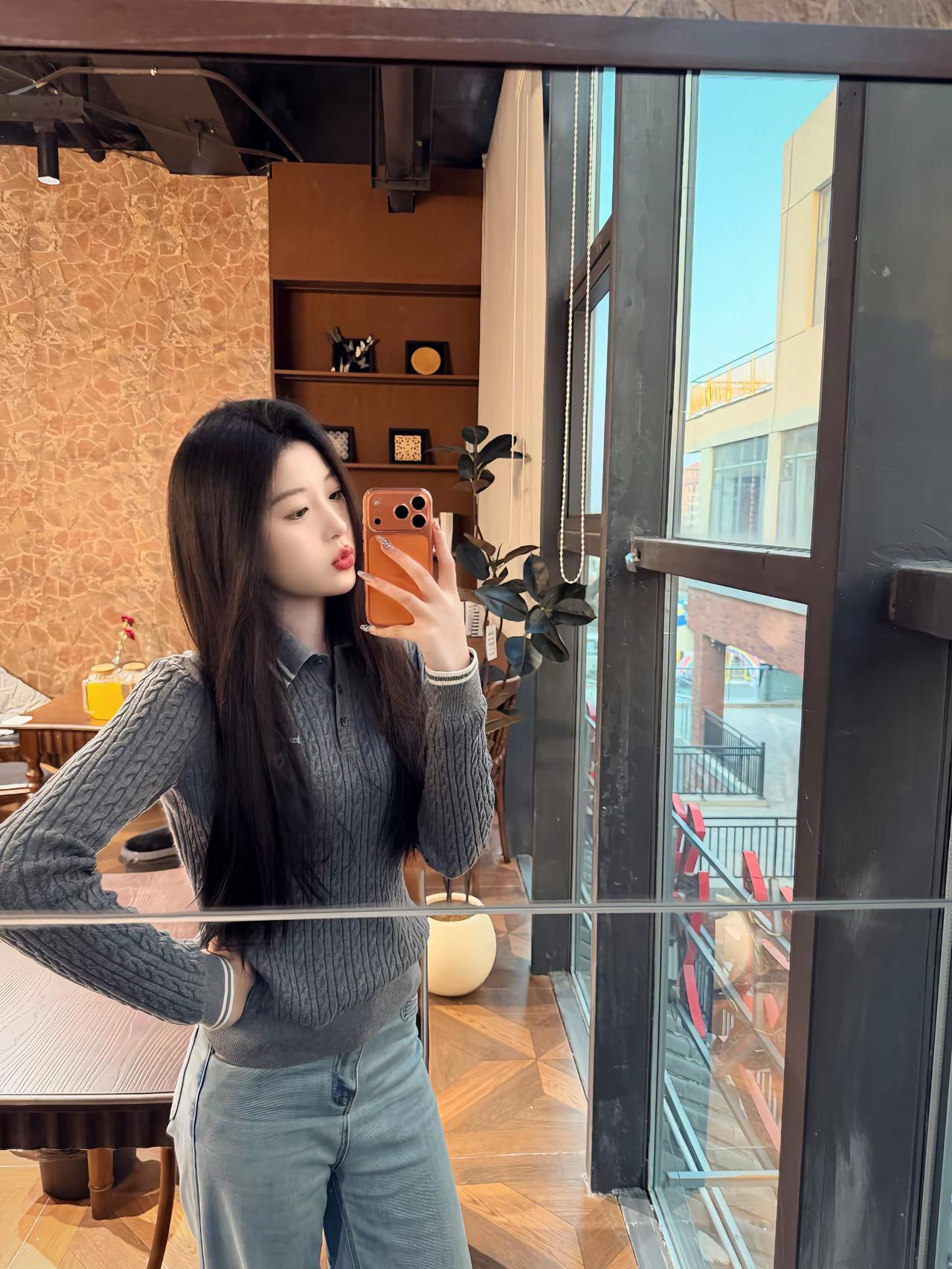 女生在室内自拍，背景有植物和窗户。
