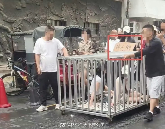 逆天，2女子与狗被关铁笼游街 ，上面写着偷人，但跟狗关一起是啥意思？  何某低俗