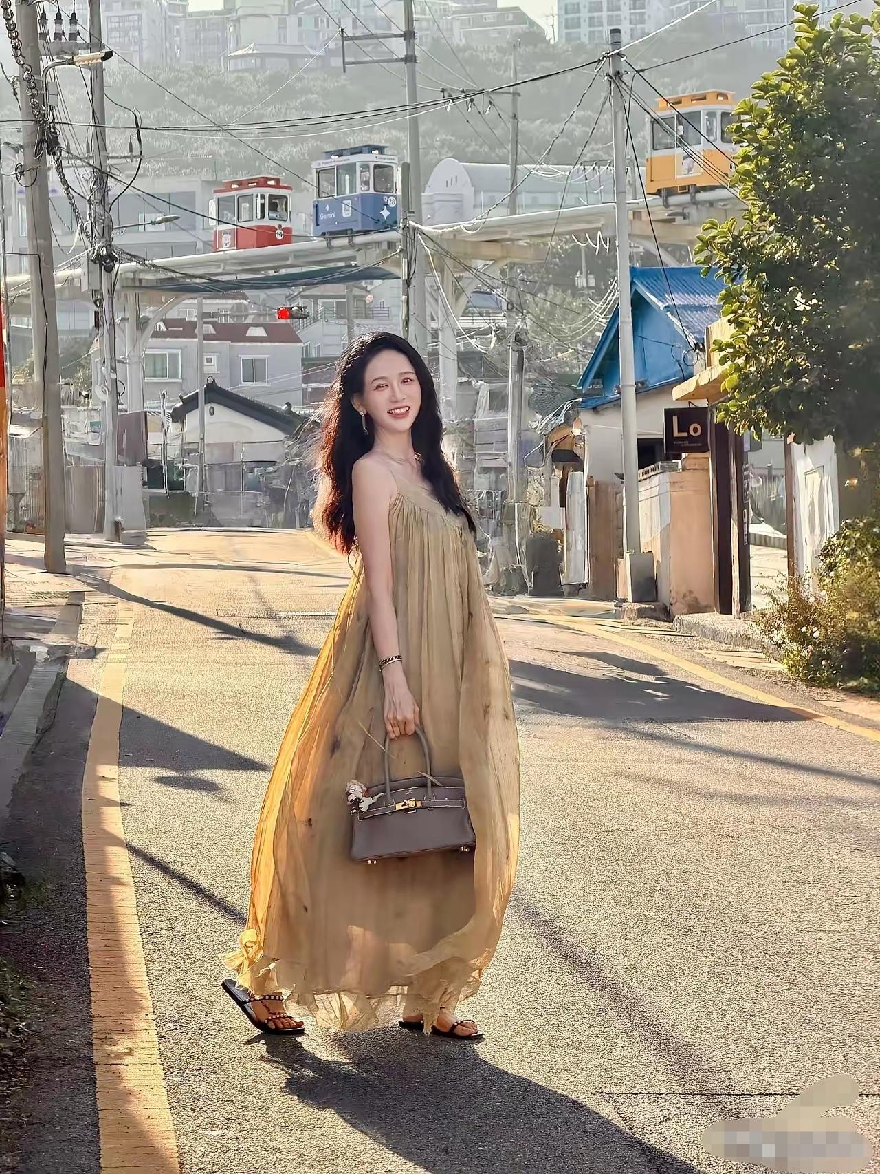 这个女人太漂亮了。魅力十足的样子妥妥的风情万种。她一袭金黄色的吊带沙裙，穿着性感