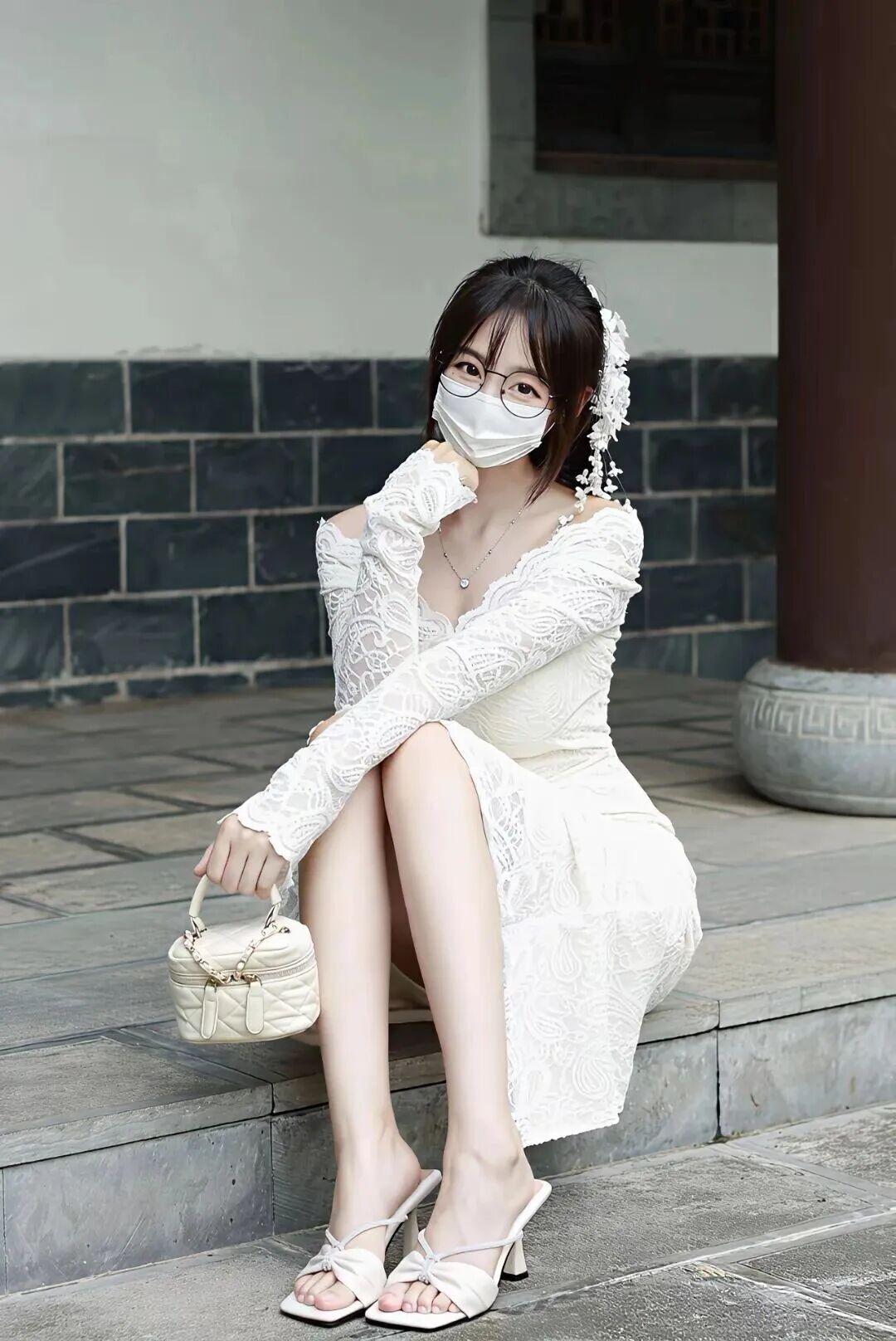 图片中，一位女性穿着一件白色蕾丝连衣裙，裙子设计为露肩款式，她双手轻拉裙领，姿态