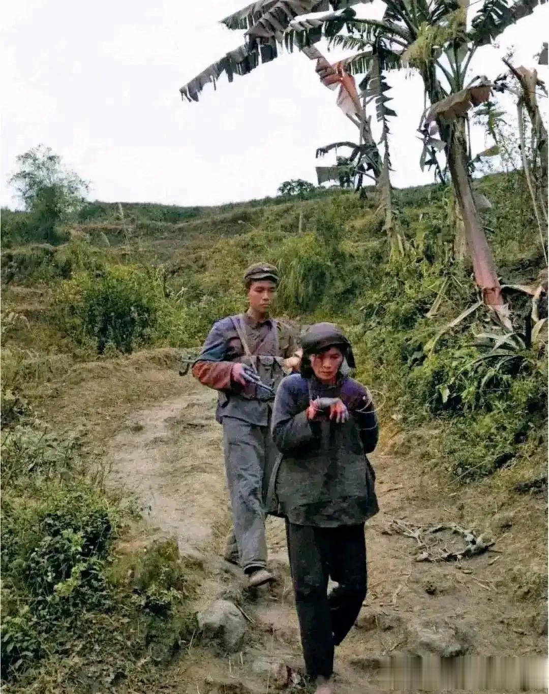 对越自卫反击战期间，一名战士押解着被俘虏的越南女特工正在赶路，注意看，照片中这名