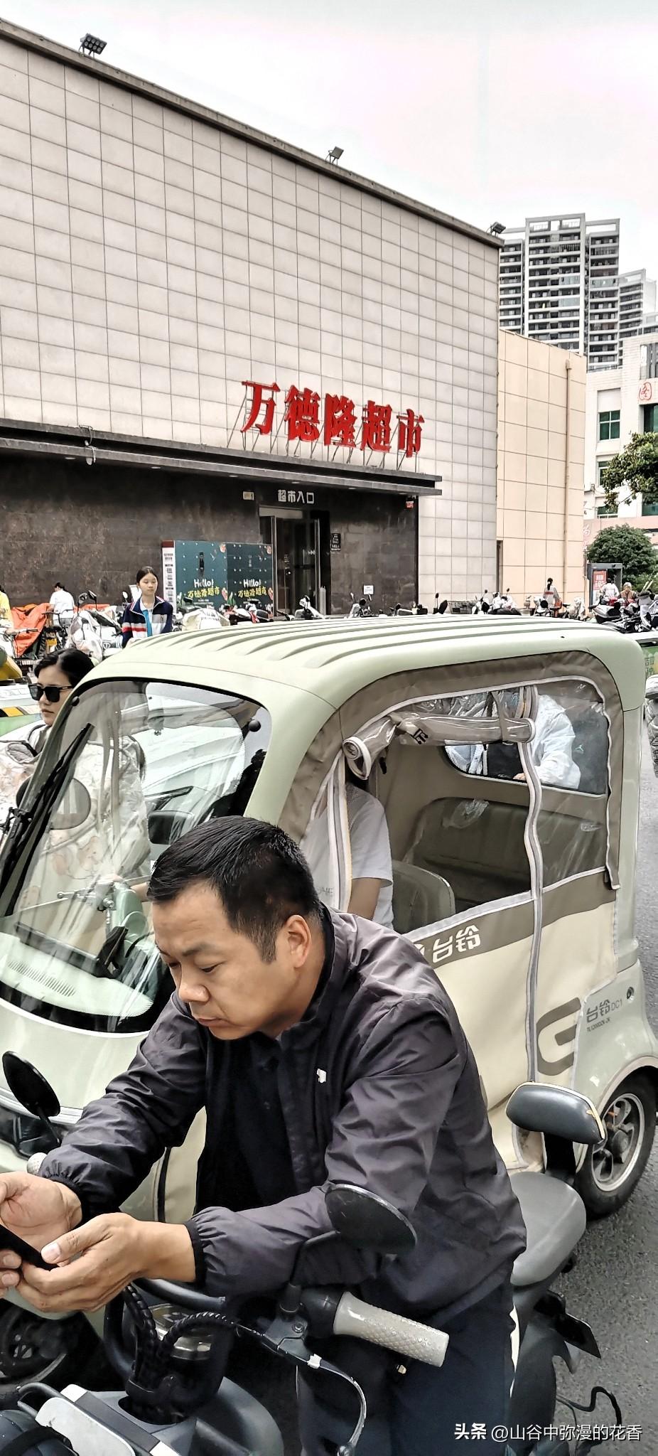 今天路过万德隆超市门口，又被这热闹的街景给戳中了。绿白相间的台铃小三轮挤在车流里