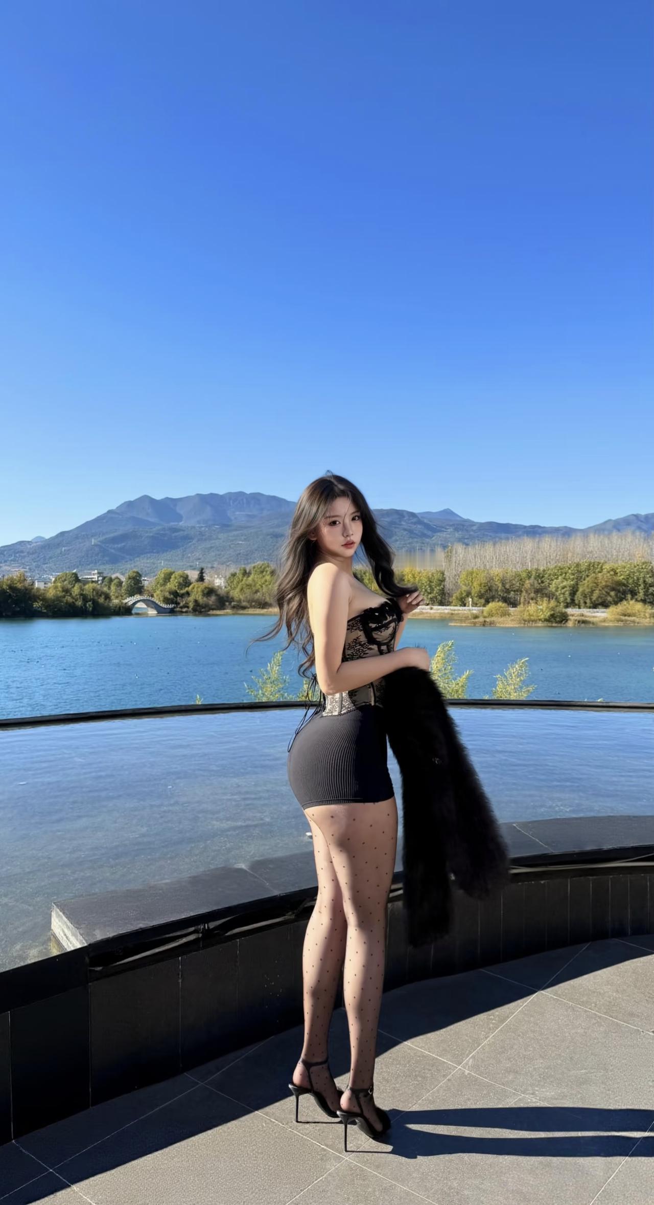 阳光下的她像是从画里走出来的人——长发顺着肩线垂成温柔的弧度，蕾丝抹胸衬得肩颈线