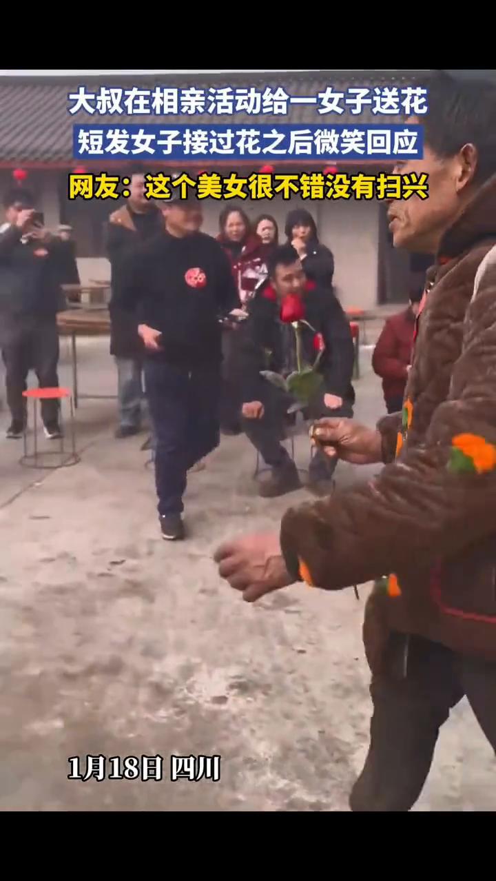 大叔在相亲活动给一女子送花，短发女子接过花之后微笑回应。网友：这个美女很不错，没