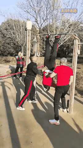 大妈这样锻炼身体太危险了

大妈把脚挷在单杆上，两个大爷站在地上推着转圈圈，看着
