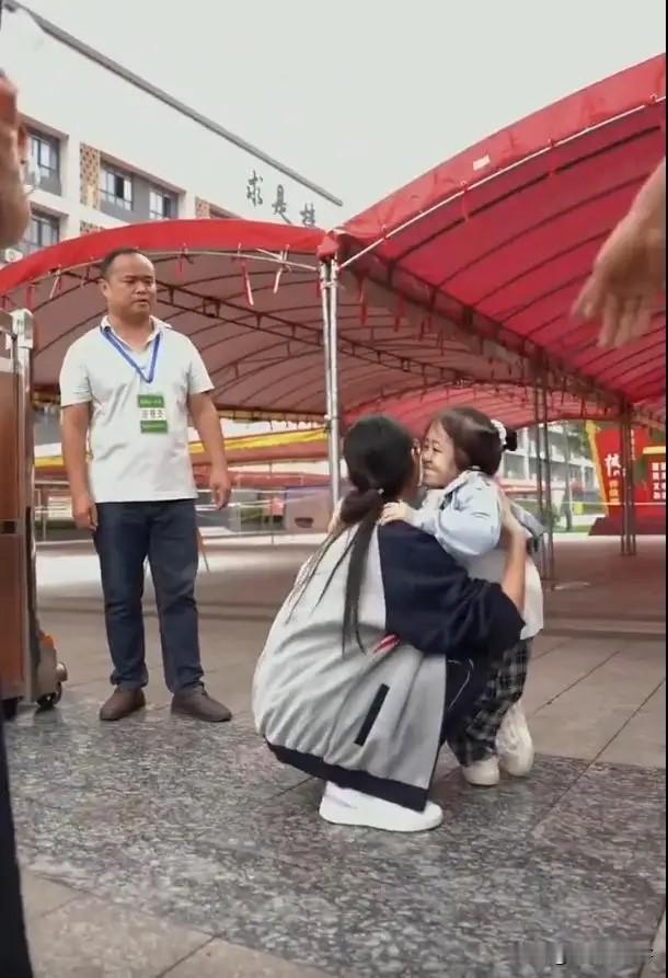 贵州，女生走出考场后，第一时间跑向一个“小女孩”。女生熟练地弯下腰，抱起女孩，穿