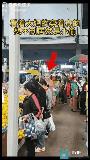穿搭一身粉色衣服，头发花白的大妈拎着一袋水果走向一个摊位，见顾客较多伸手掏向年轻