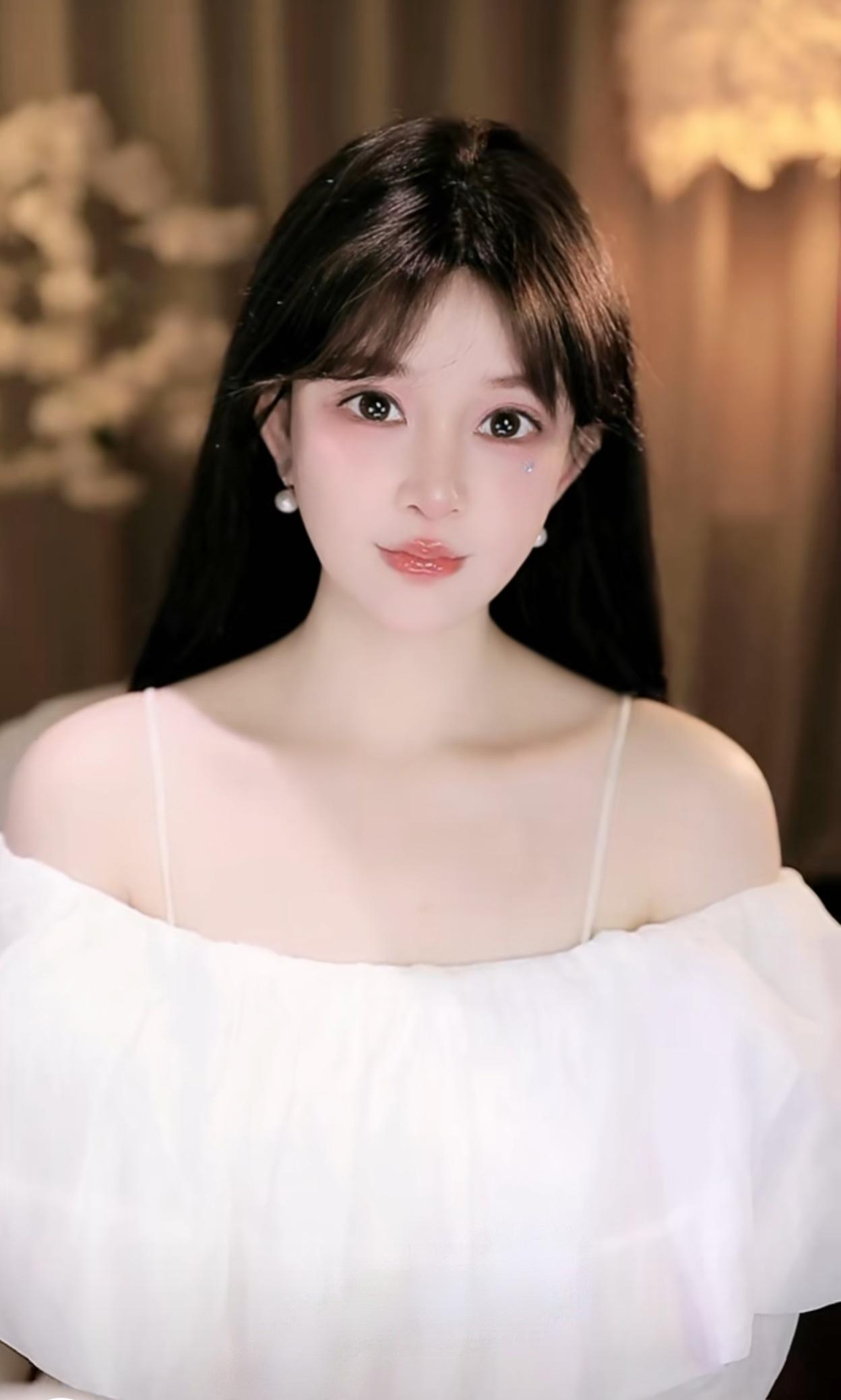 她留着一头乌黑柔顺的长直发，空气刘海衬得脸庞愈发小巧精致。肌肤白皙胜雪，眉眼清澈