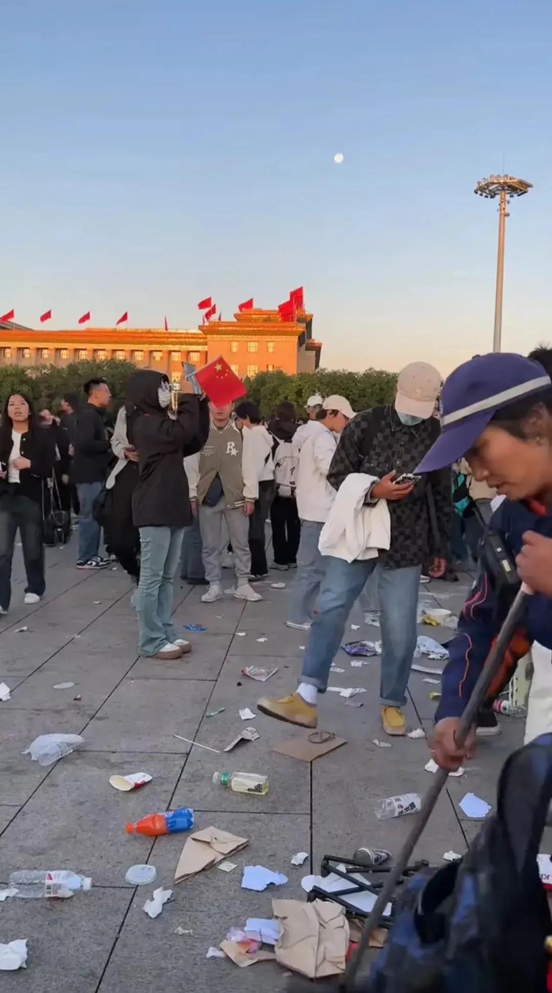 垃圾遍地的天安门广场，一个环卫工人正在清扫垃圾，很难想象这是升旗仪式之后留下的场