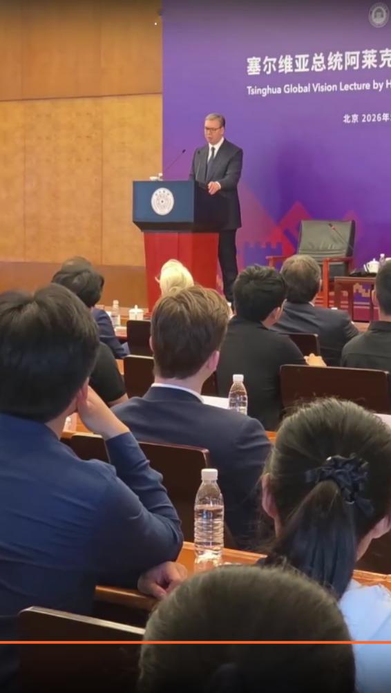 5月26日武契奇在北京第三天到访清华大学，站在台上演讲，台下学生举着手机拍照；他