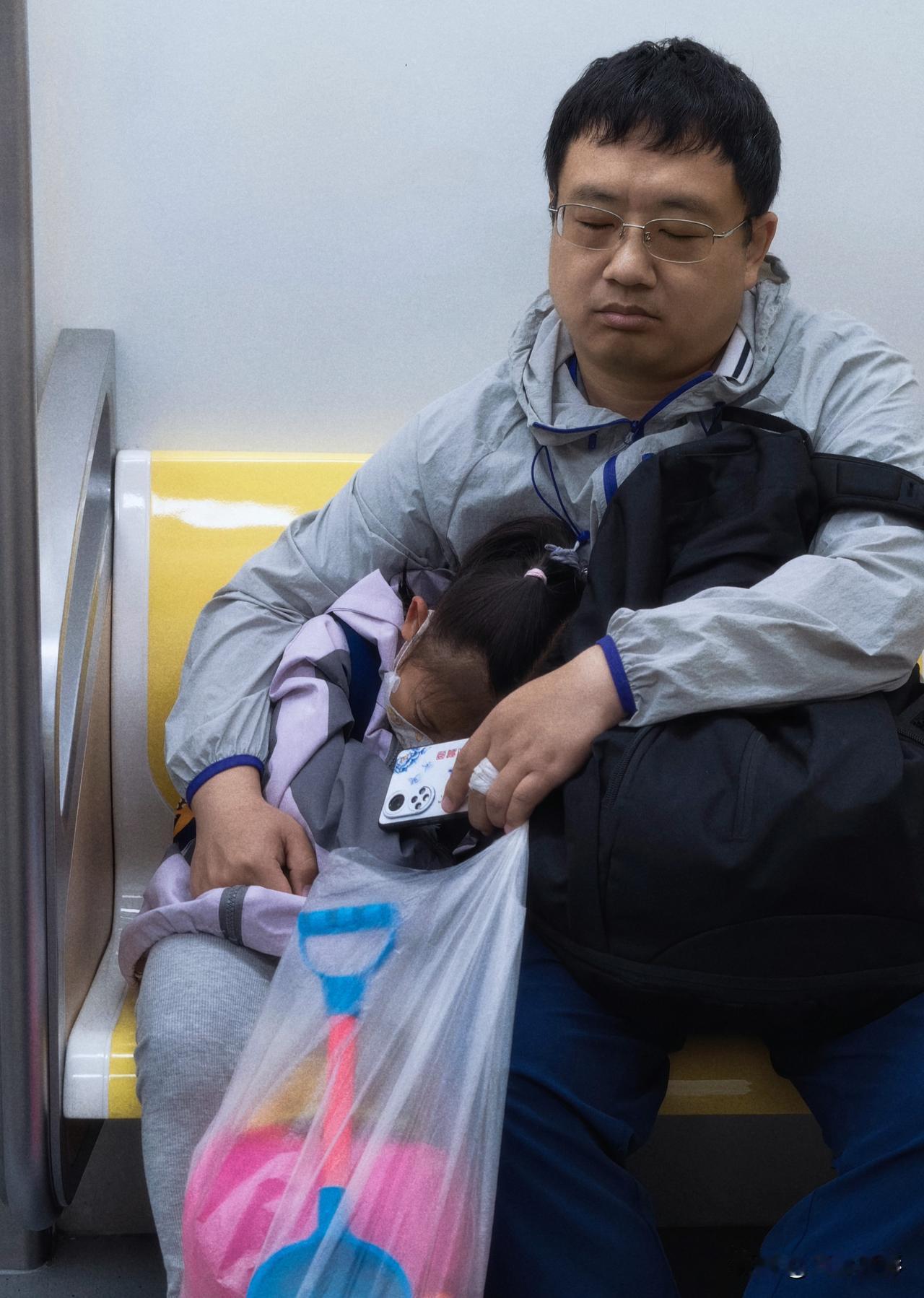 周末带着孩子去户外活动，回家途中，父女俩在地铁上都累了。