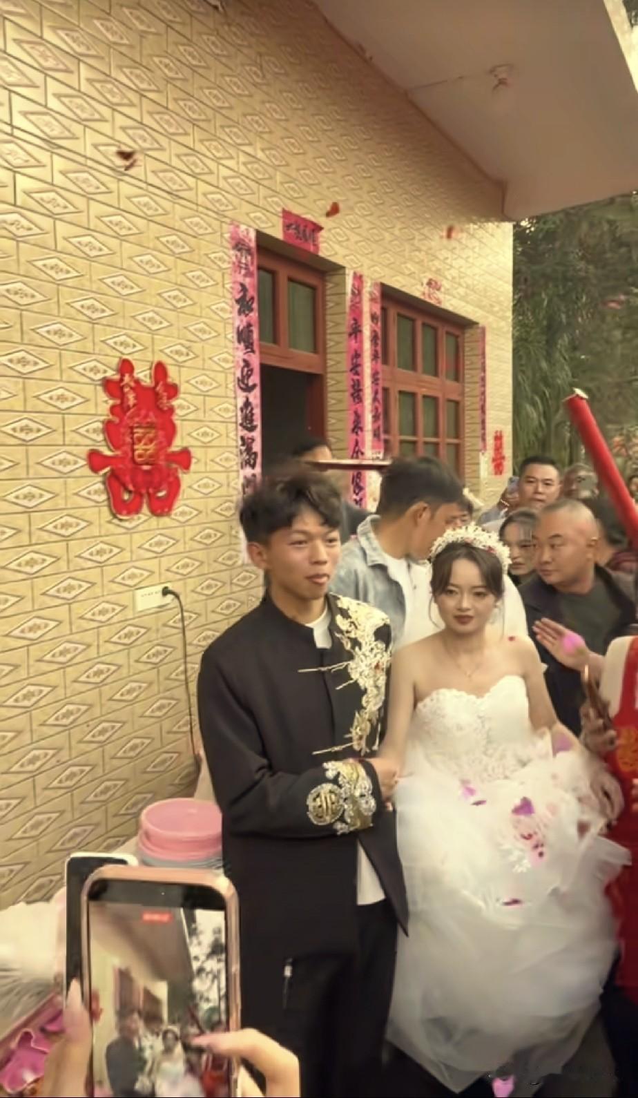 小小徐害羞了！他穿着一身中式礼服，媳妇穿着白婚纱，在大家的欢呼声中，从屋里走了出