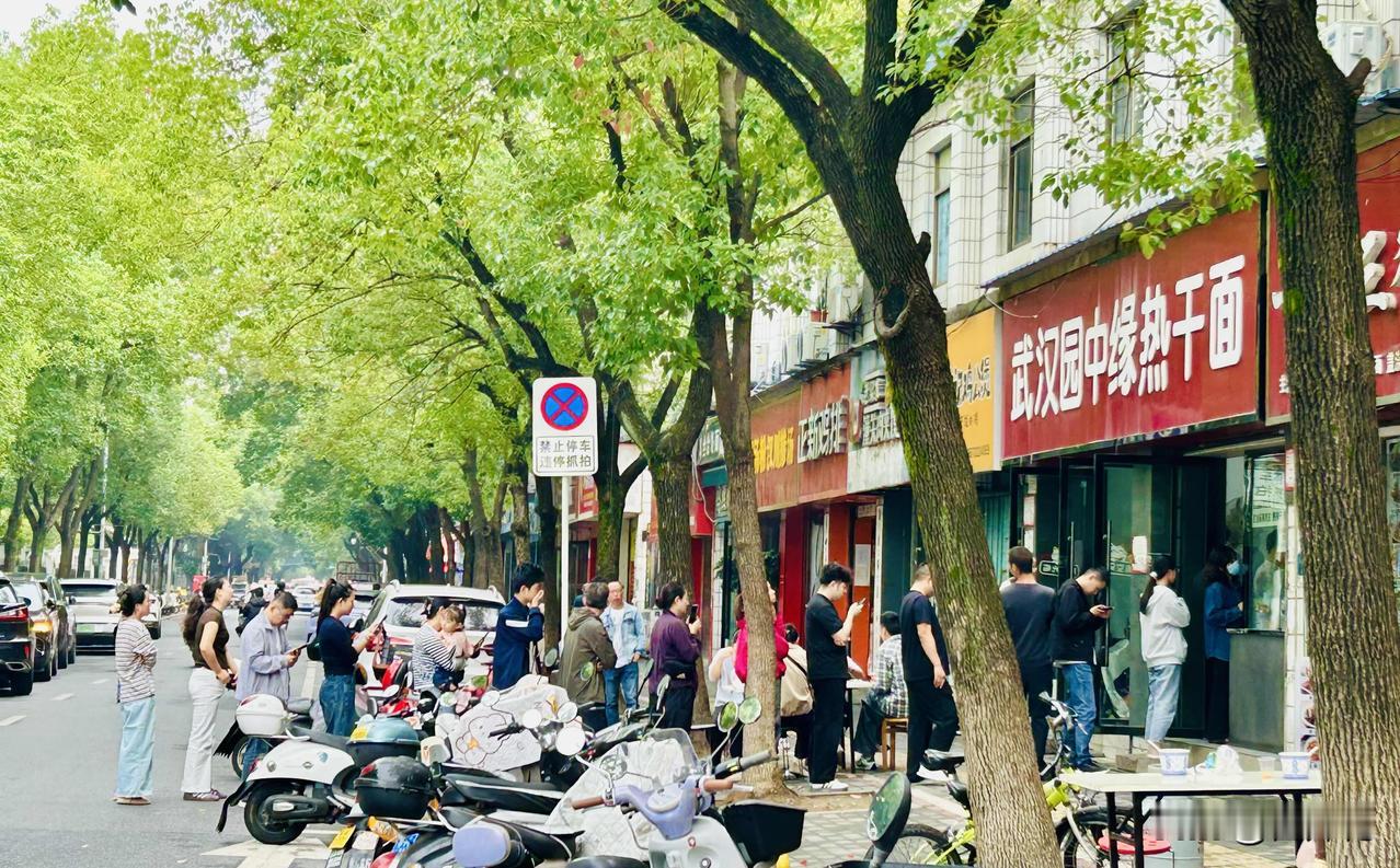 热干面馆前大排长龙（随手拍）。上午九点半，孝感红光街上的一家热干面馆门前早已排起