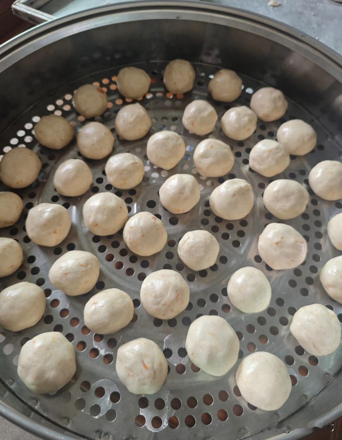 今年冬天的不同蒸笼里码满圆滚滚的团子，浅白面皮裹着细碎橙纹，蒸汽将漫出软香。一个