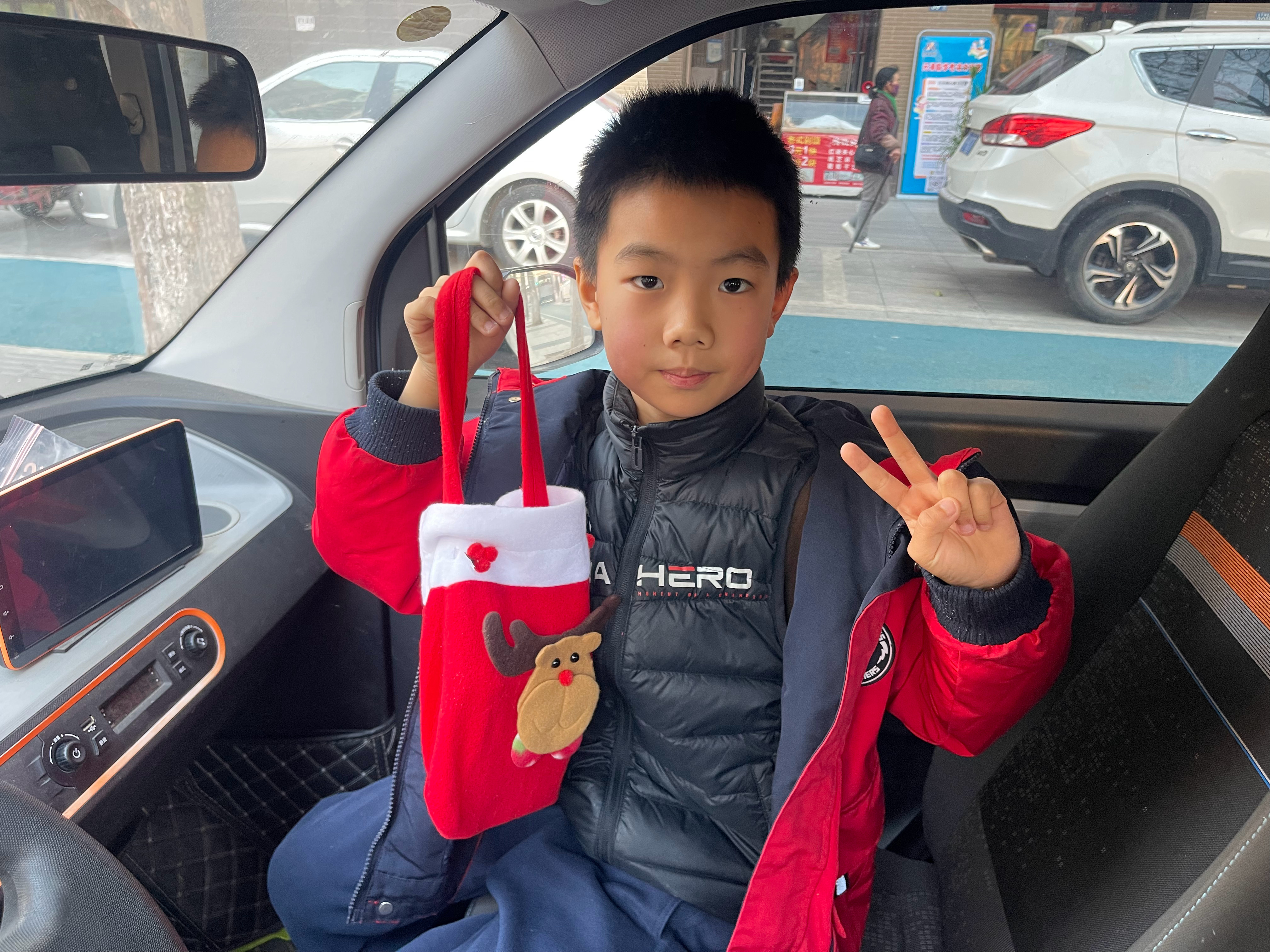 今天圣诞节提前接小胡同学放学，学校发礼物了，他非要把袋子提了，生怕我吃了他的小零