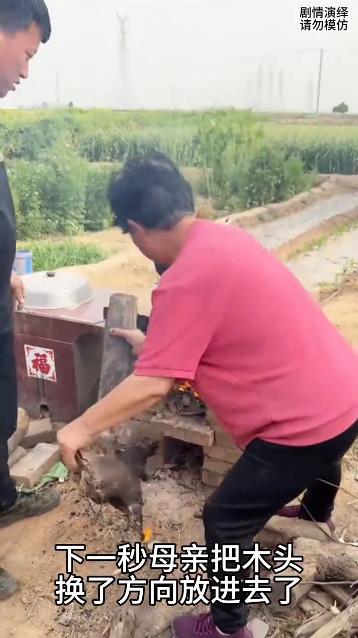 儿子拿着木头怎么都放不进灶火里，下一秒母亲的做法太有才了。
母子两个正在烧火做饭