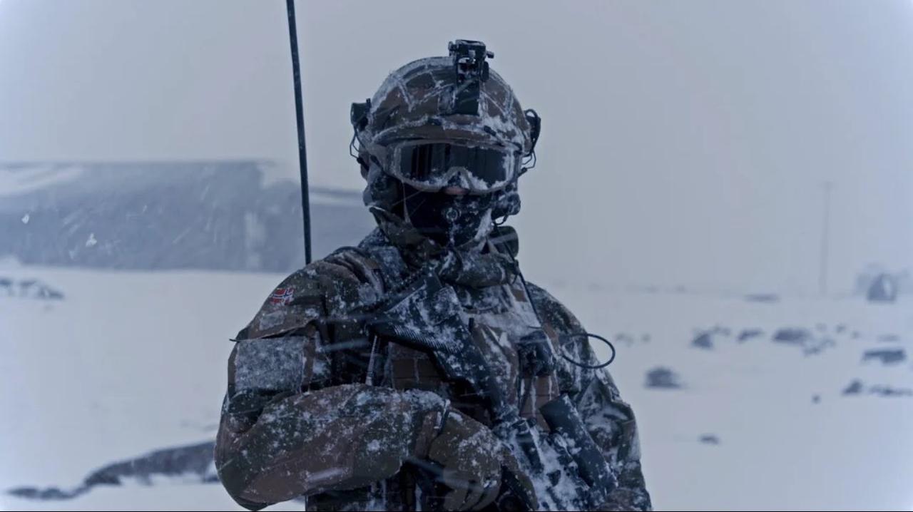 照片中一名身着全套冬季装备、浑身雪白的挪威士兵正在冰岛凯夫拉维克空军基地执勤，这