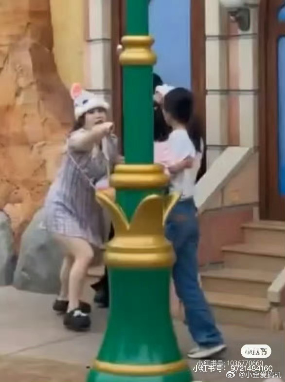 迪士尼一对情侣和一家三口打起来了很多人都在那排队拍照，那对情侣拍照的时候那个小孩