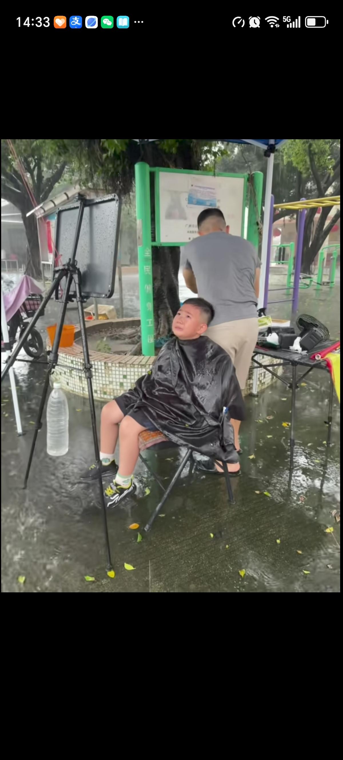 小男孩被强迫在雨天露天剪头发，大风呼呼的刮着，大雨哗哗的下着，抵不住他心里的伤心