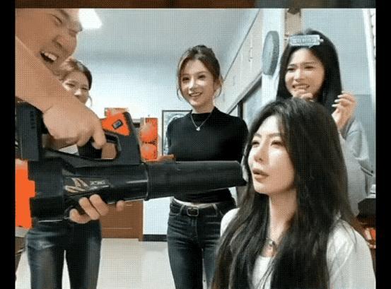 旁边几位女生淡定围观，只有前面这位，被喷枪直接冲击到五官起飞，嘴巴张得老大，头发