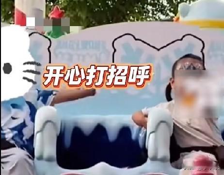 近日，山西一游乐园里，3岁半的小女孩坐在游乐设施上，旁边小男孩伸出手臂(只有半截