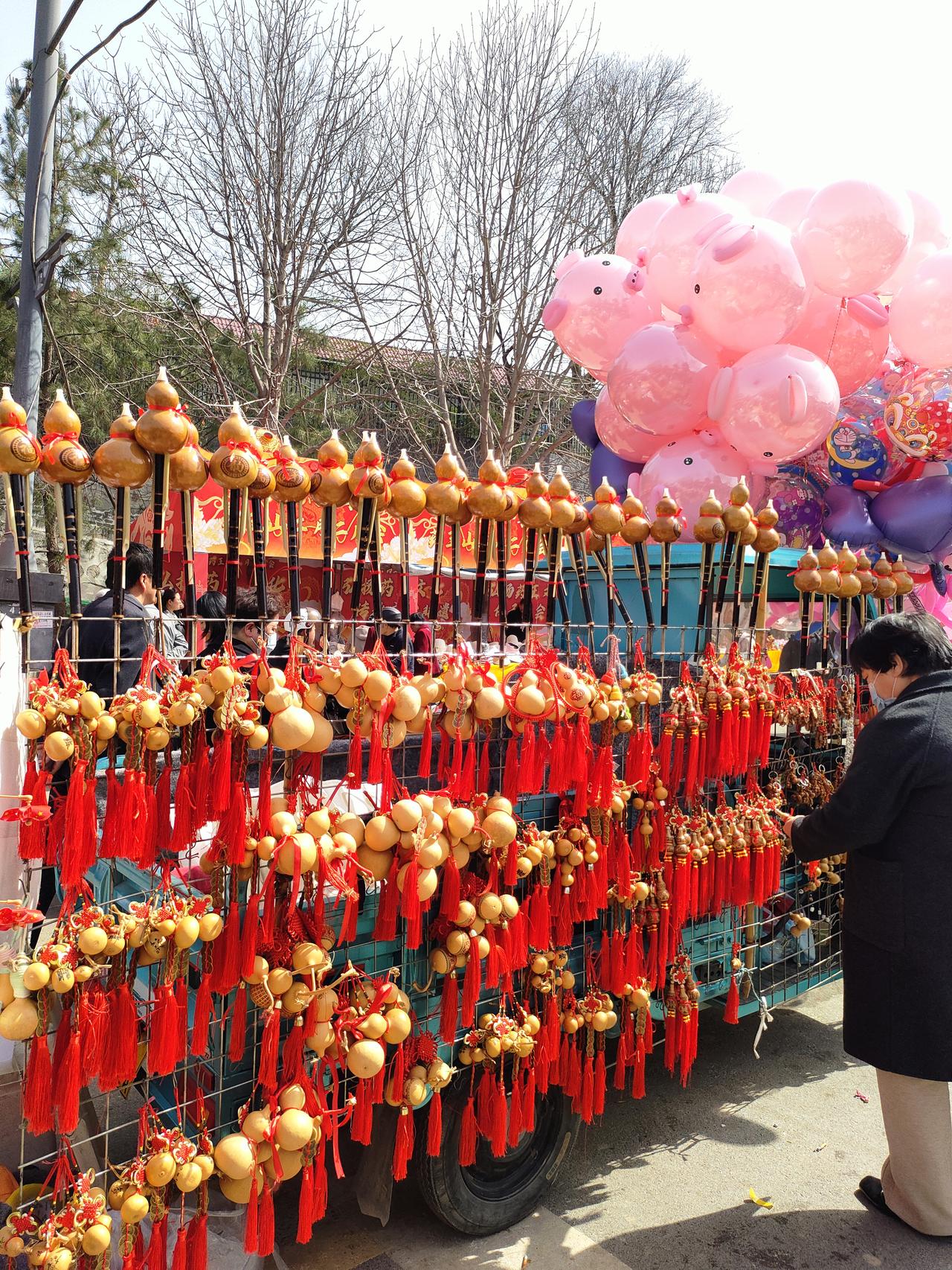 葫芦挂起福禄，红穗摇来喜气，
粉猪气球飘着热闹，
春日集市里，
满是人间烟火与岁