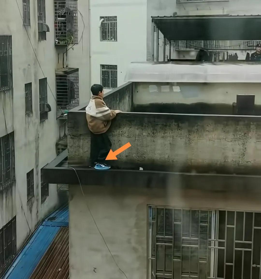 一小学生站在楼顶外边沿欲跳楼被消防员和警察谈心后获救。