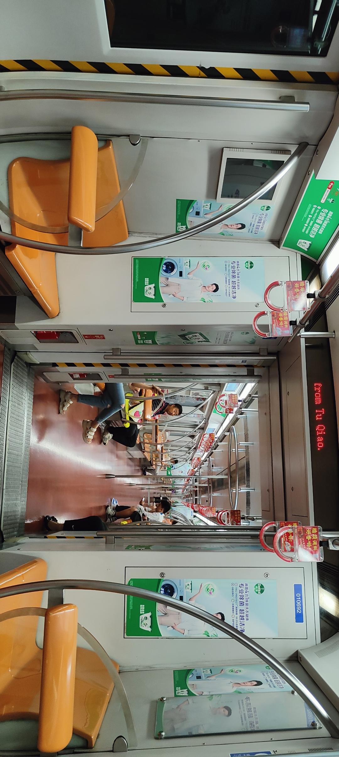 地铁车厢里的日常：乘客们井然有序地站立，车厢干净整洁，广告牌清晰可见。