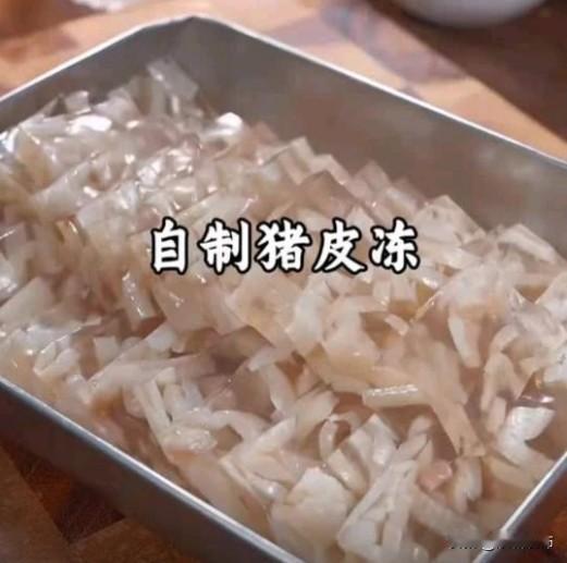 猪皮冷水下锅，加姜片、料酒焯水去腥，煮好后捞出刮净内层油脂，这是皮冻透亮不腻的关