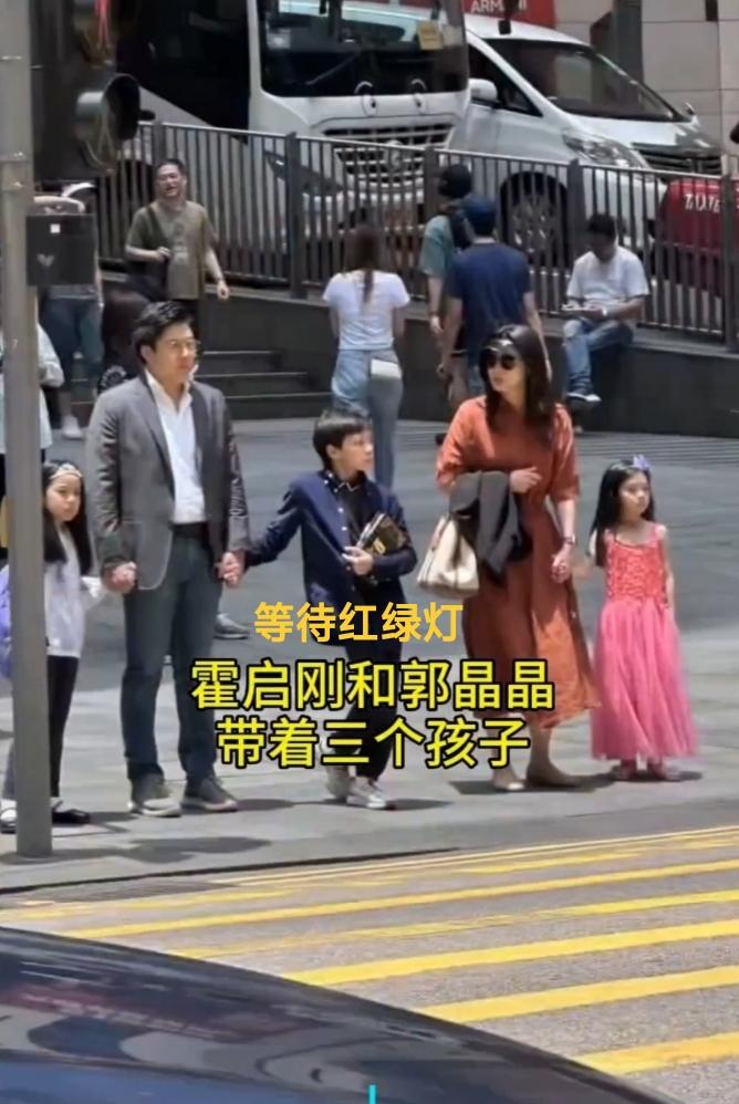 香港街头，霍启刚与郭晶晶带着三个孩子准备过斑马线，身边不见一个保镖或保姆。这样朴