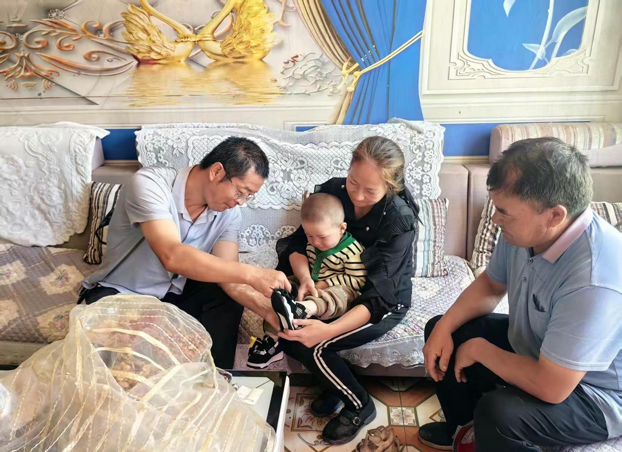 送童鞋到农户  关心下一代。2026.6.23，托万买里村，干部走访把上级带来的