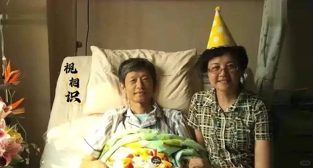 2016年，病痛的艾跃进在病床上的照片，而妻子付洪陪伴在旁，镜头中的艾跃进露出了...