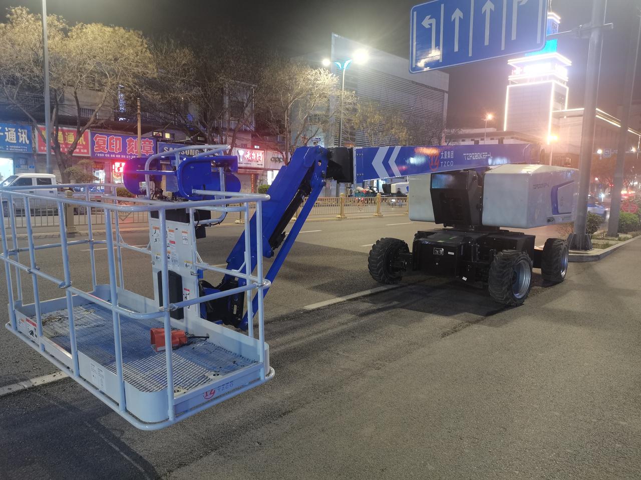 晚上出去溜达，看见一辆蓝色的升降车停在路边。

车臂高高升起，托着一个人，正在解