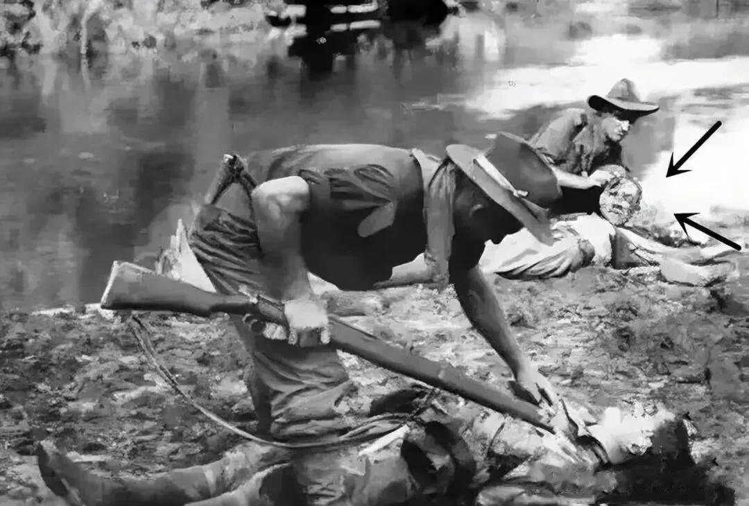 1945年，太平洋战场，一名澳大利亚士兵在打扫战场时，用刺刀剥下一名战死的日本士