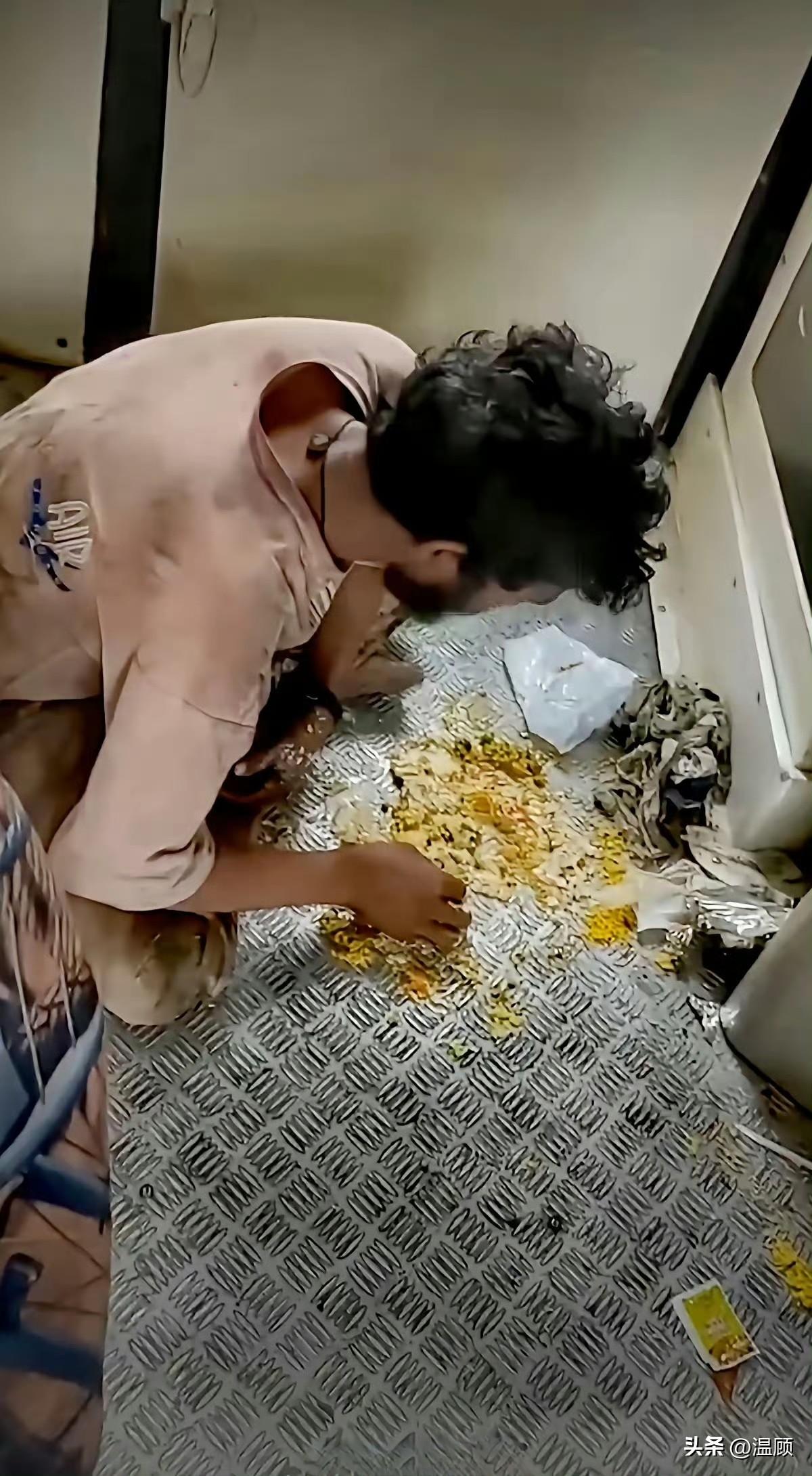 印度火车的车厢连接处，一名男子正蹲在带有菱形花纹的金属防滑钢板上，直接用手抓取拌