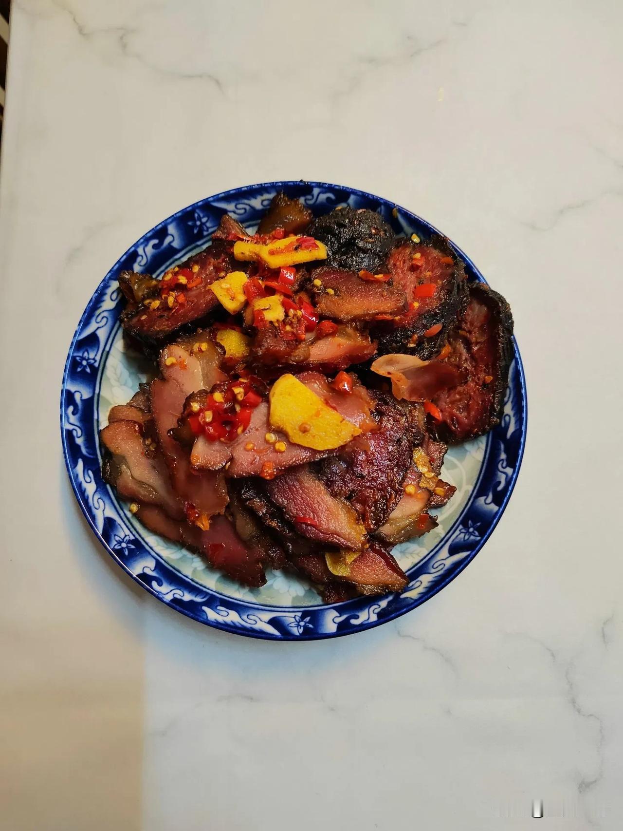铁锅在灶上滋滋作响，当青烟升起的时候，案板上的腊肉闪烁着琥珀色的光泽。这是年前从