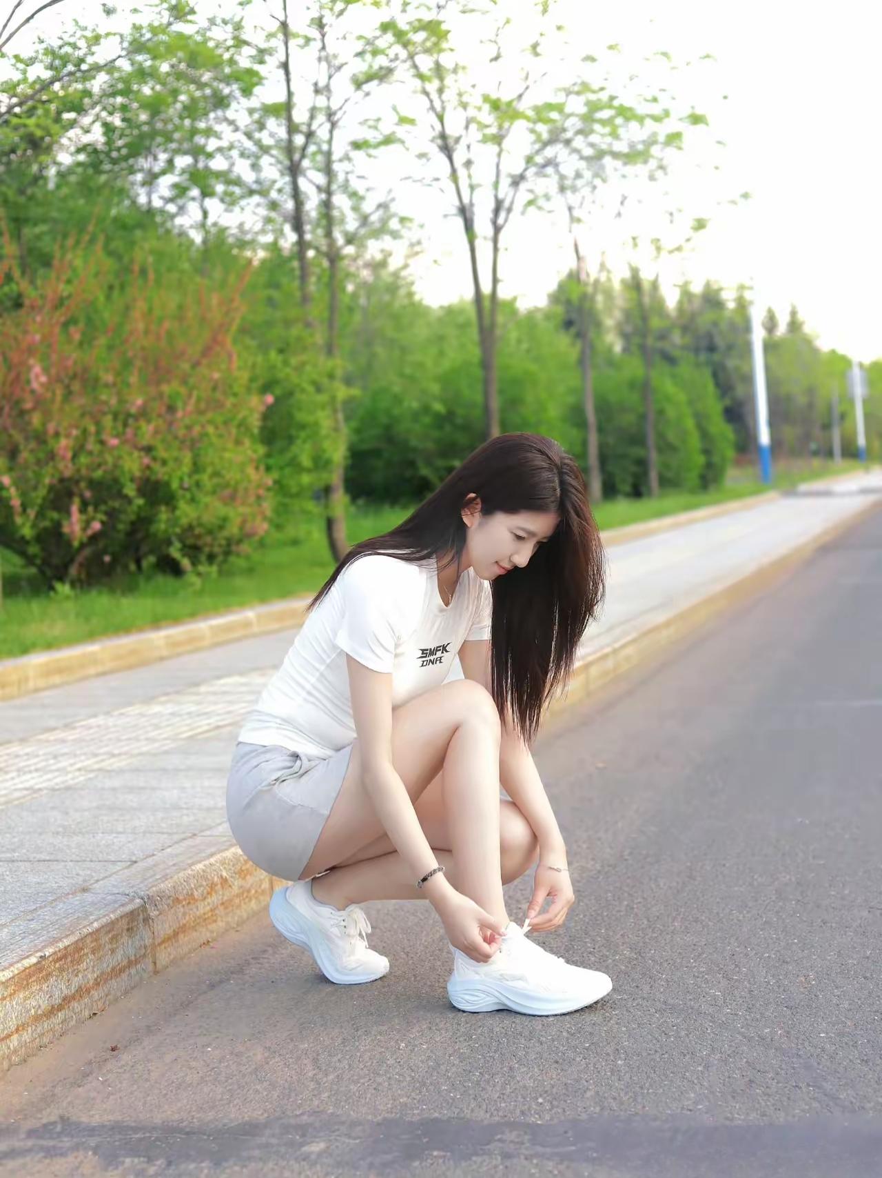 阳光明媚的午后，元气少女在绿意盎然的小路上系鞋带，青春洋溢！🌞👟💚