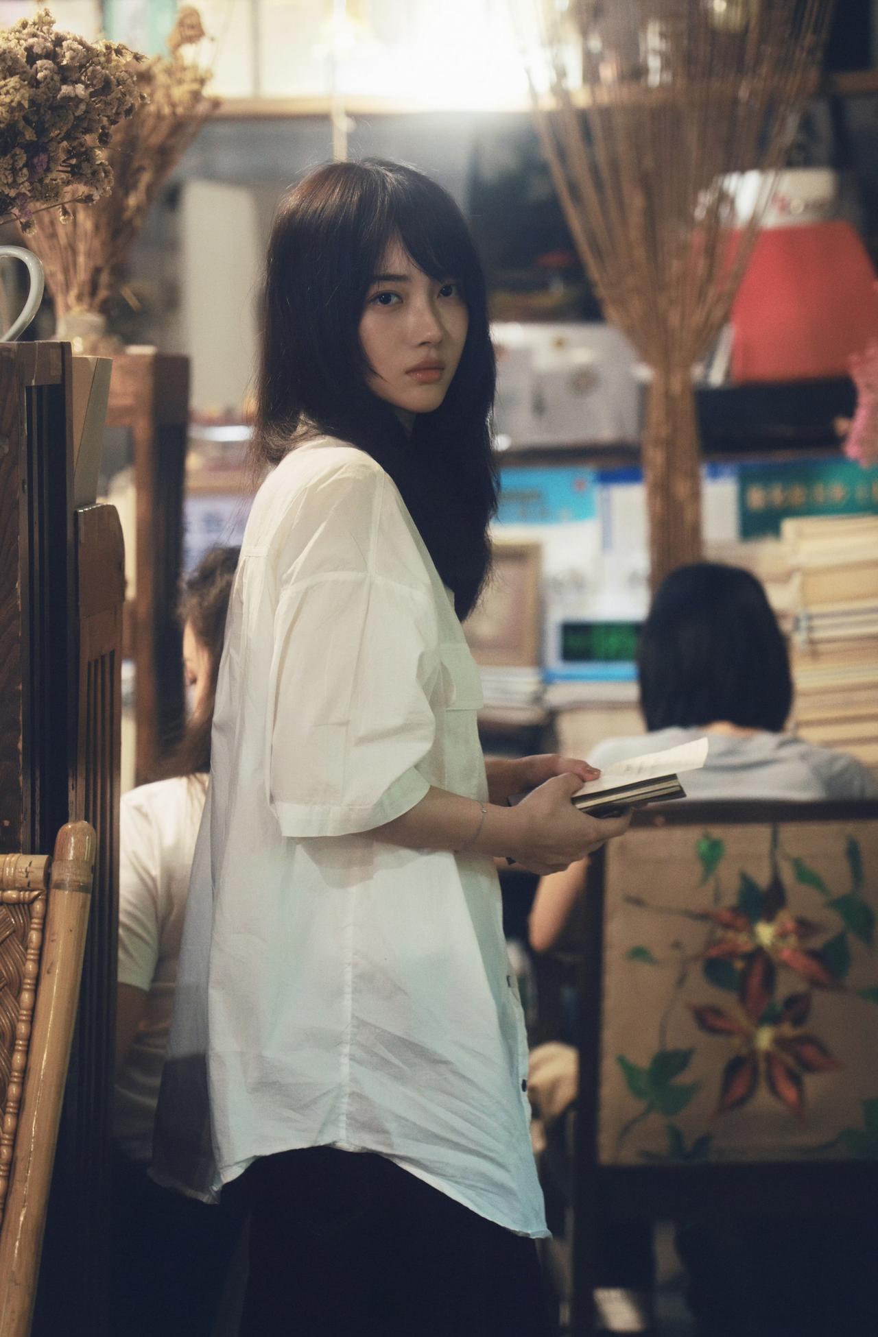 她像从旧电影里走出来的女主角，

白衬衫、旧书店、绿植与花，还有手里的书…

连