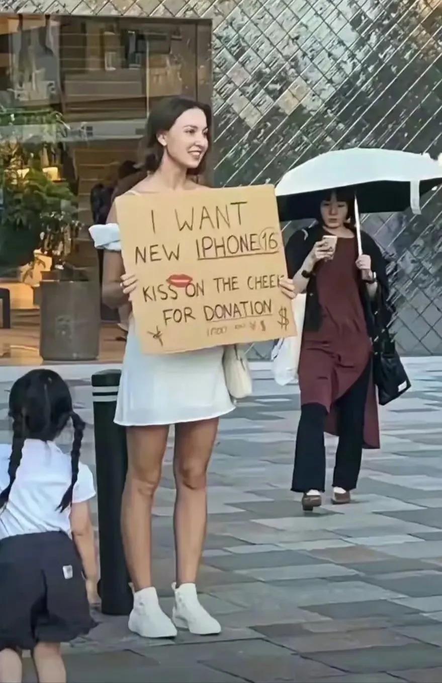 这个站街女举的牌子上的意思是，“她需要新的苹果16手机，谁能捐助她，她就亲亲谁的