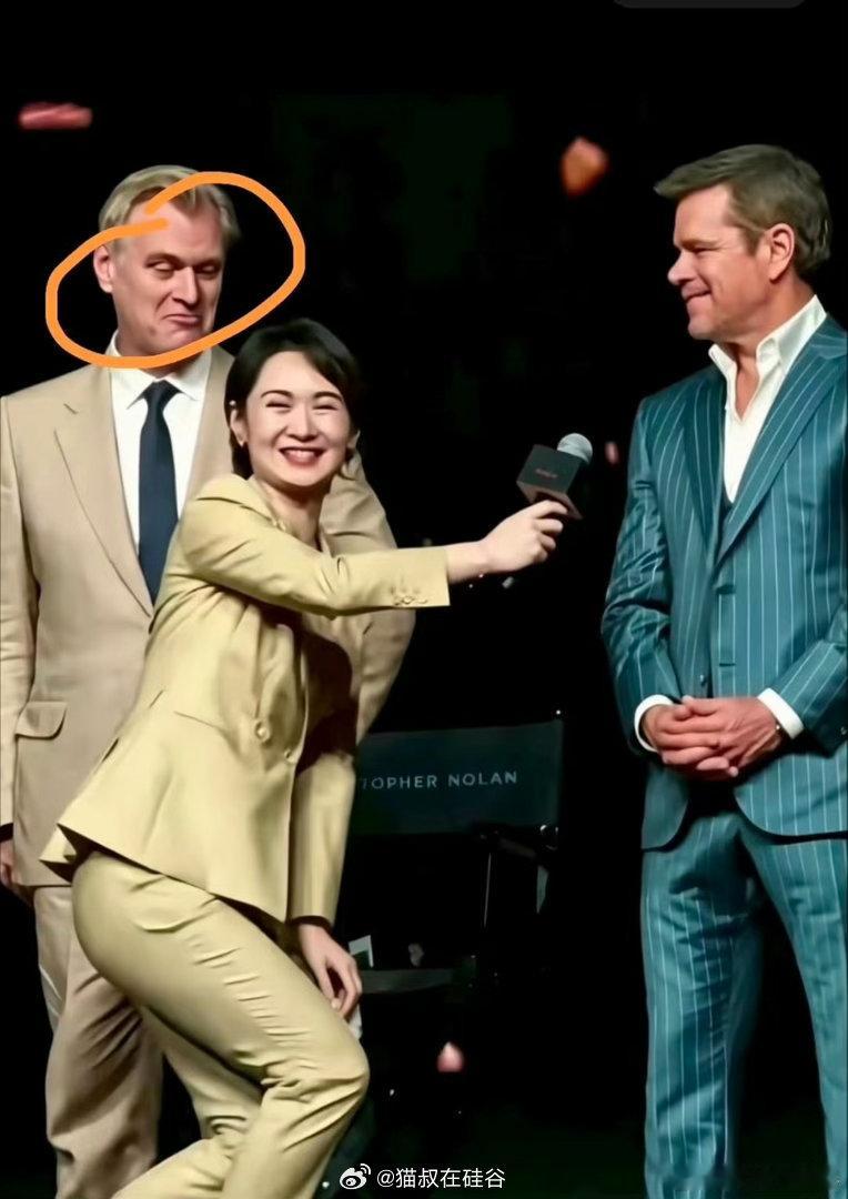 这其实是一个半蹲递麦的动作，是电视台在外取景采访直播的习惯动作，避开近距离的摄像