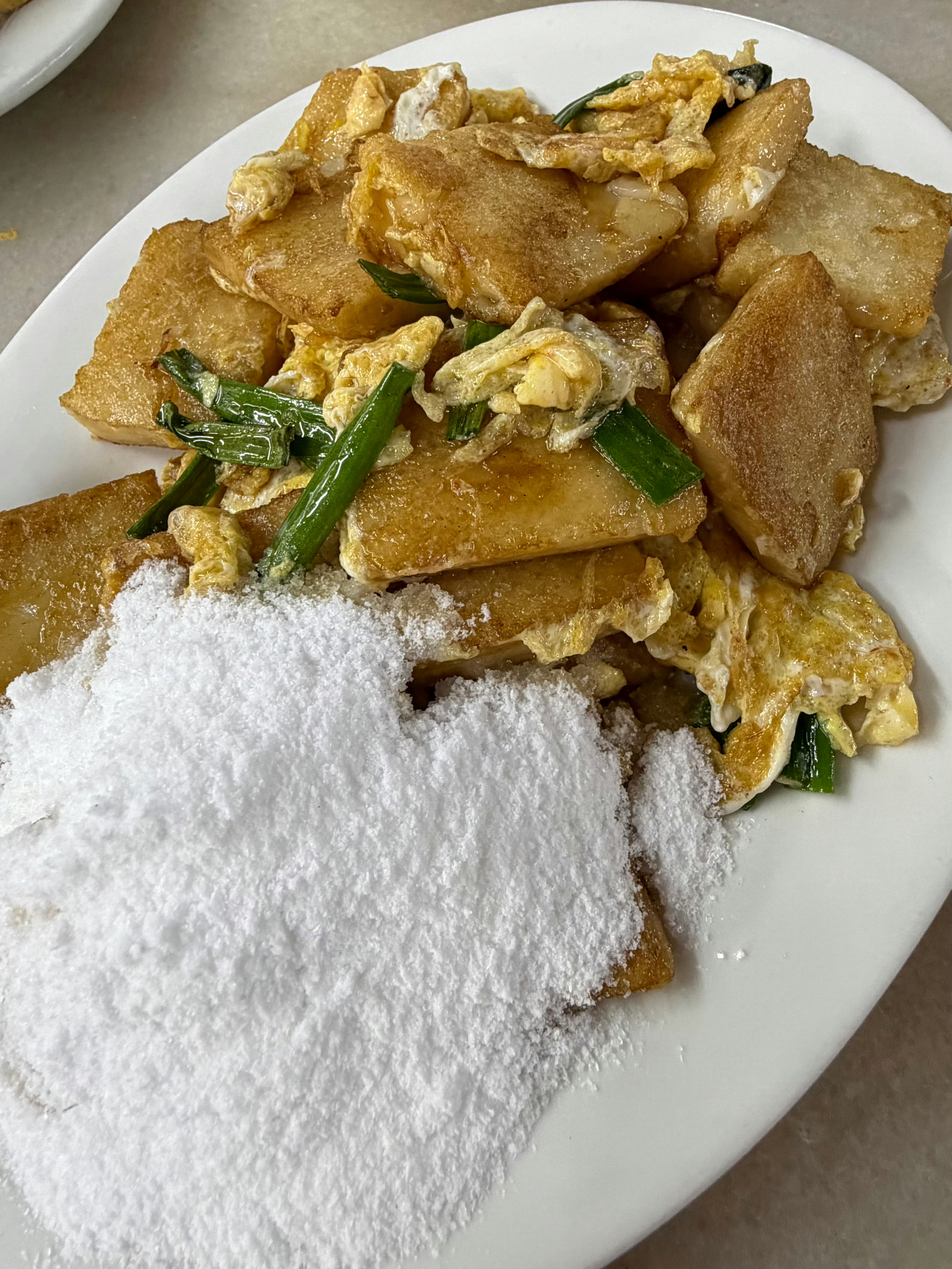 汕头特色美味一盘咸的炒咸粿边上还有一堆白糖粉可以纯吃咸的也可以蘸白糖吃一半咸一半