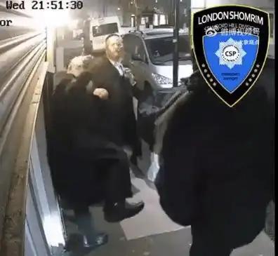 当地时间4月15日21点，英国伦敦，2名犹太拉比在街头卷帘门前，1人在打电话，他