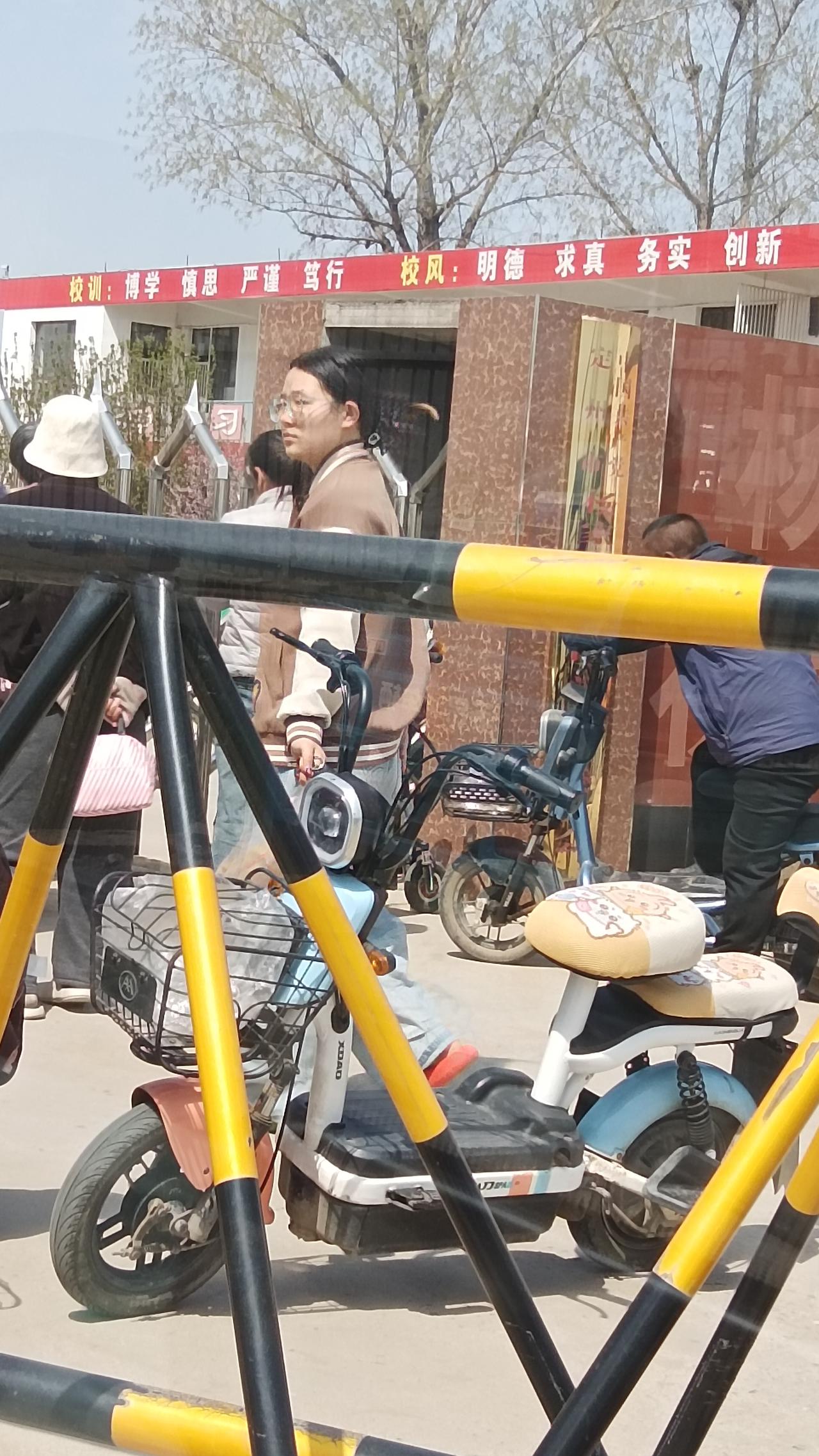 校园门口的日常：学生、电动车、校训标语