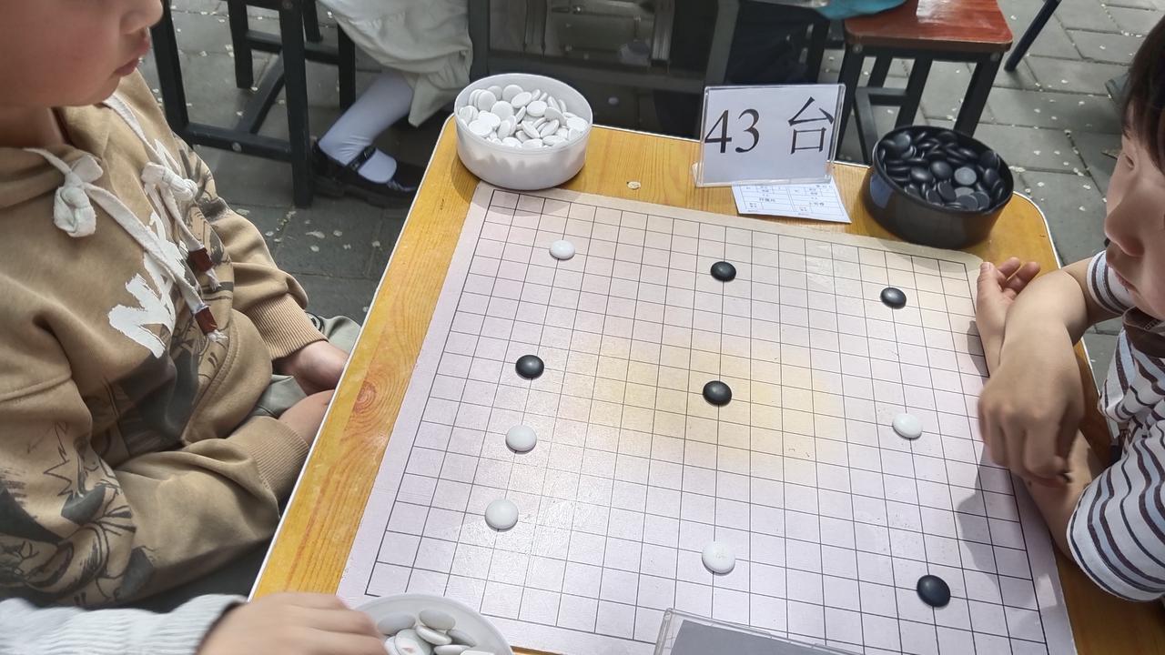 童趣满溢，黑白棋子于棋盘上展开较量，那是童年的快乐时光。温暖春日，阳光透过斑驳树