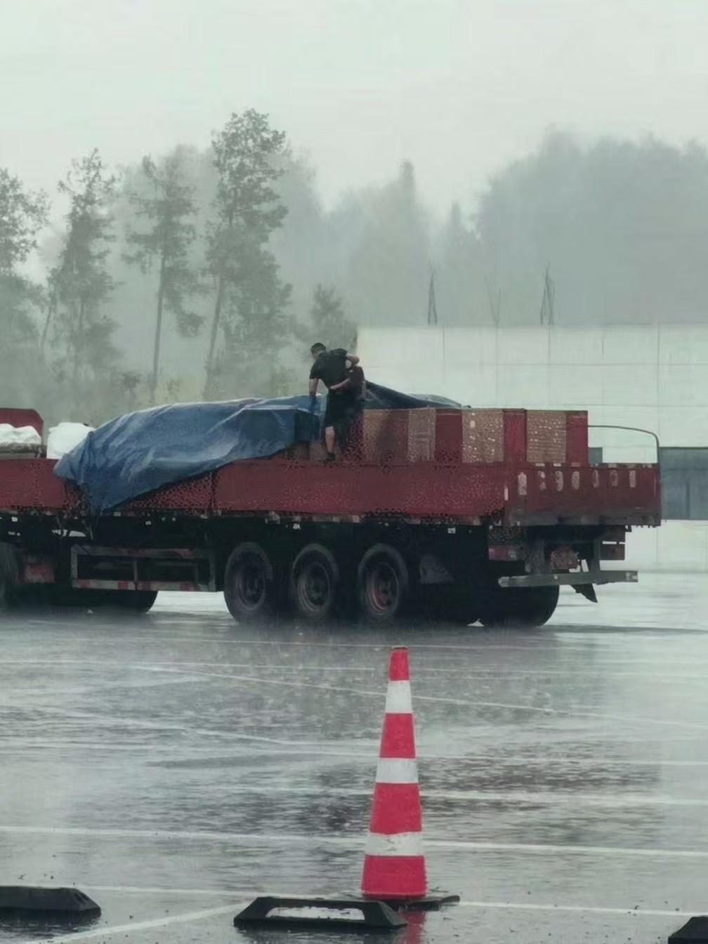 重庆，高速上暴雨一来就来。货车司机在服务区里一个人和一块吸饱了水的帆布较劲，走一