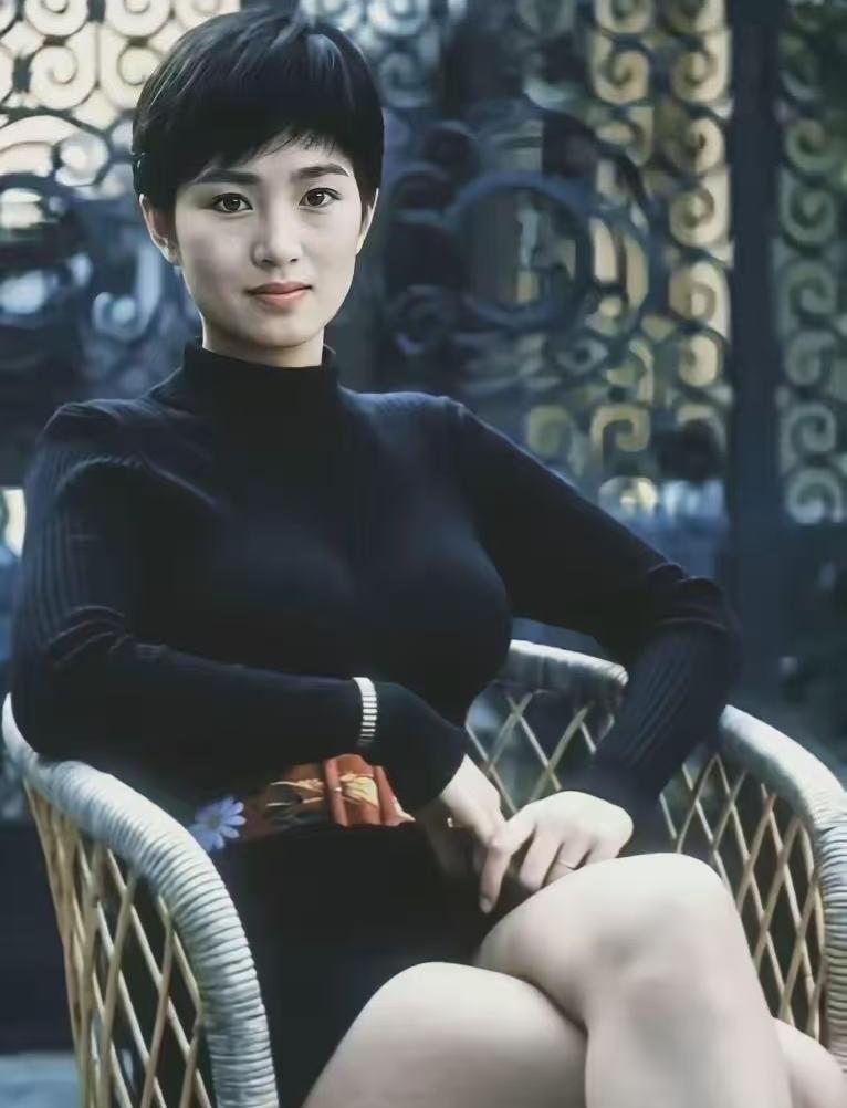 能猜出这位是谁吗？
一张早年的抓拍旧照，利落短发搭配朴素毛衣，随性坐在藤椅上。身